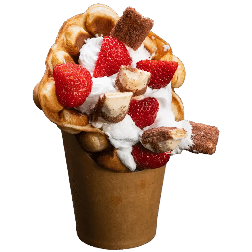 Bubble waffle topped with whipped cream, strawberries, and chopped pieces of Kinder Bueno.