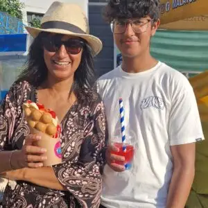 A woman holding a bubble waffle and smiling with a young person holding a layered slush drink.