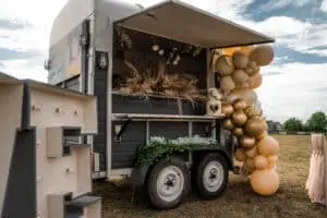 Side view of the bubble waffle trailer decorated with pampas grass, neutral balloons and trailing greenery.