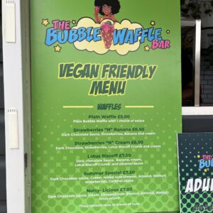A bright green sign displaying The Bubble Waffle Bar’s vegan-friendly menu options.